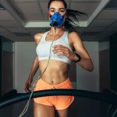 Kobieta w masce biegowa na bieżni, mierząca VO2 max.