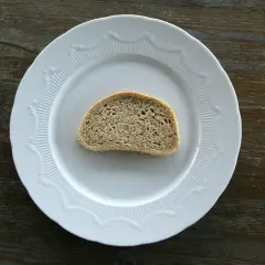 Jedna kromka chleba na białym talerzu. Zastanawiasz się, ile kromka chleba kcal ma?