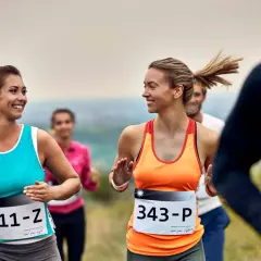Uśmiechnięte kobiety biegną w półmaratonie. Ile km jeszcze do mety?