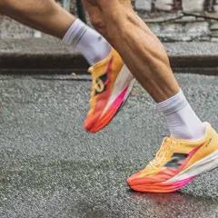 Biegacz w kolorowych butach do biegania, idealnych na treningi hiit, pokonuje mokrą nawierzchnię.