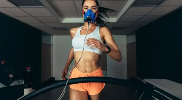 Kobieta w masce biegowa na bieżni, mierząca VO2 max.