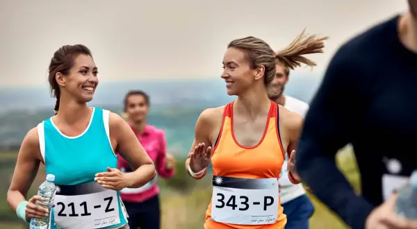 Uśmiechnięte kobiety biegną w półmaratonie. Ile km jeszcze do mety?