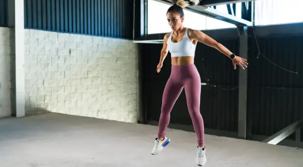 Kobieta w sportowym stroju wykonuje dynamiczny skok, pokazując, że burpee to świetne ćwiczenie.