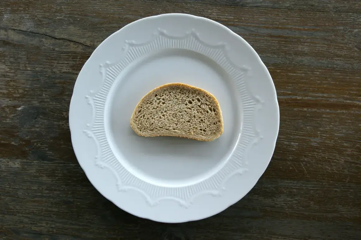 Jedna kromka chleba na białym talerzu. Zastanawiasz się, ile kromka chleba kcal ma?