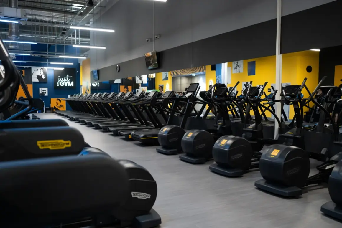 Rzędy bieżni i orbitreków w siłowni Just Gym. Dowiedz się, jak wejść na Multisport i zacząć trening.