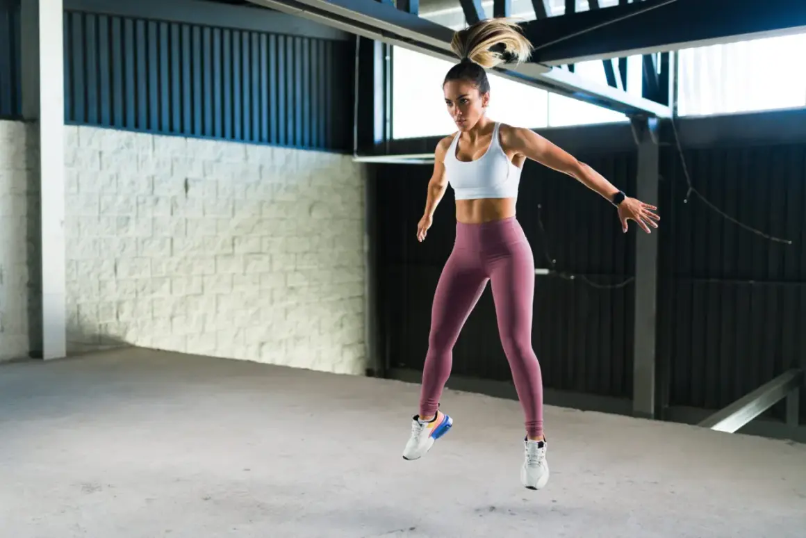 Kobieta w sportowym stroju wykonuje dynamiczny skok, pokazując, że burpee to świetne ćwiczenie.